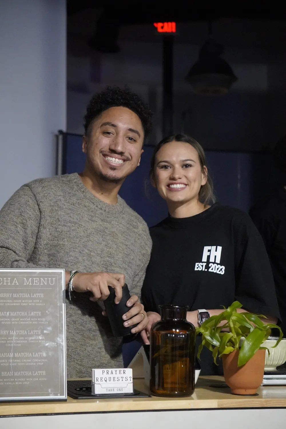 Aziel and Bri Rubero-Diaz, the husband-and-wife owners of Encounter Coffee, behind their matcha cart with the printed matcha menu