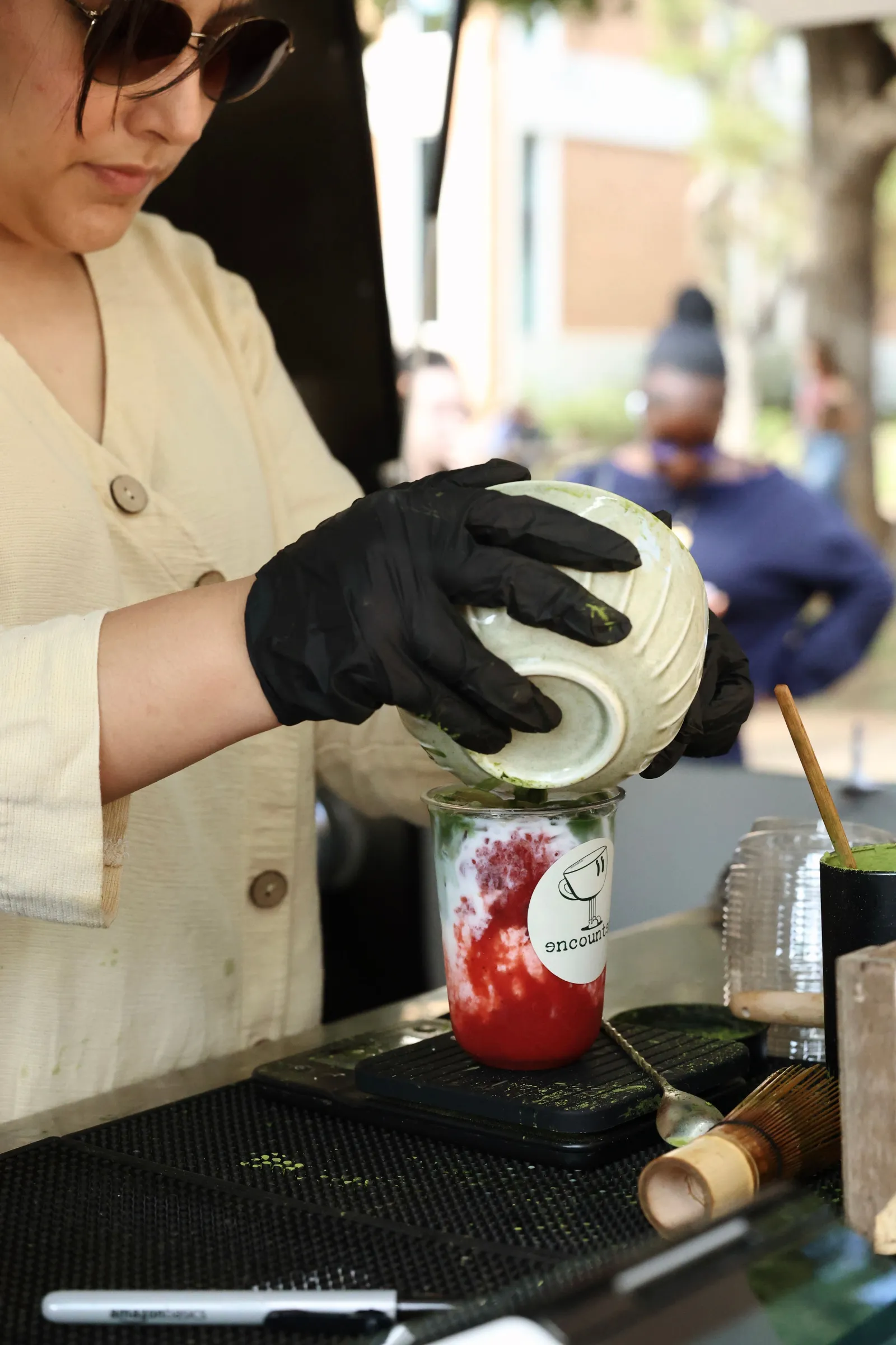 A barista pouring whisked ceremonial-grade matcha over strawberry in an Encounter Coffee cup