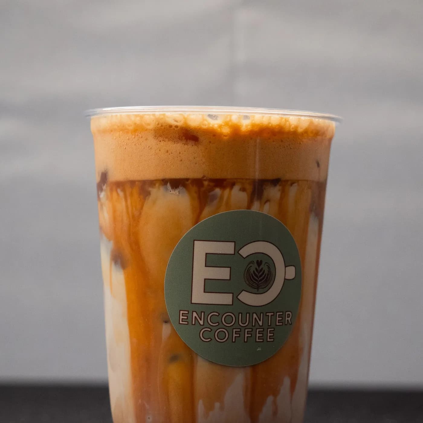 Caramel iced latte in an Encounter Coffee cup, made to order at a coffee cart catering event