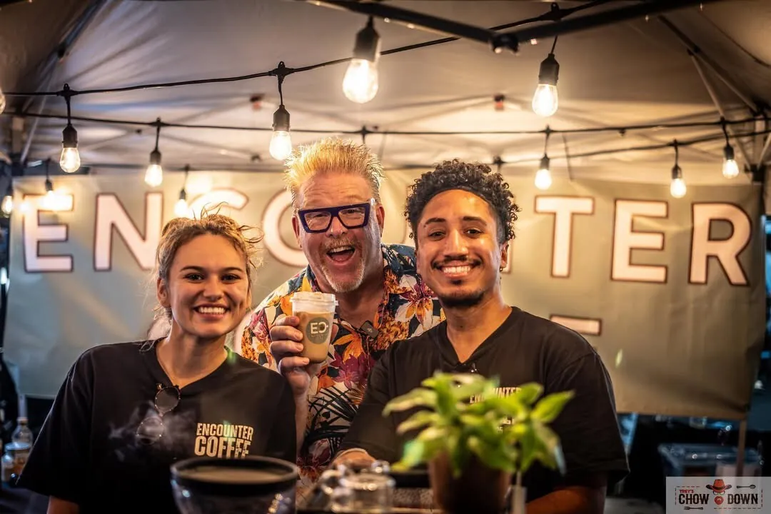 The Encounter Coffee baristas serving a guest under the ENCOUNTER banner at a DFW event
