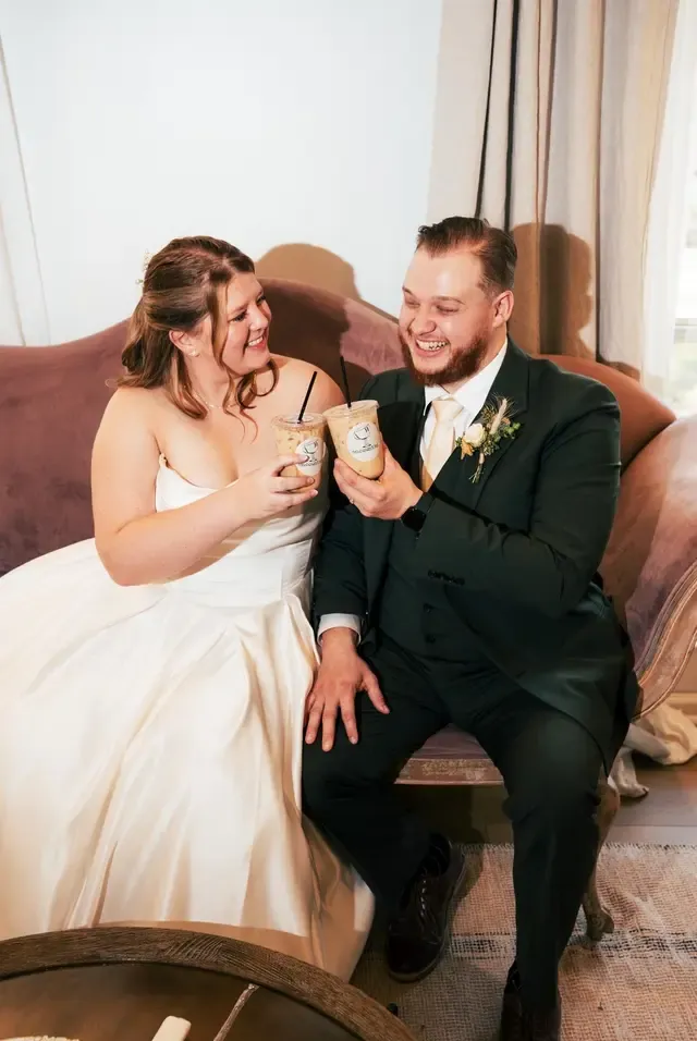 A couple toasting with iced coffees from Encounter Coffee at their wedding