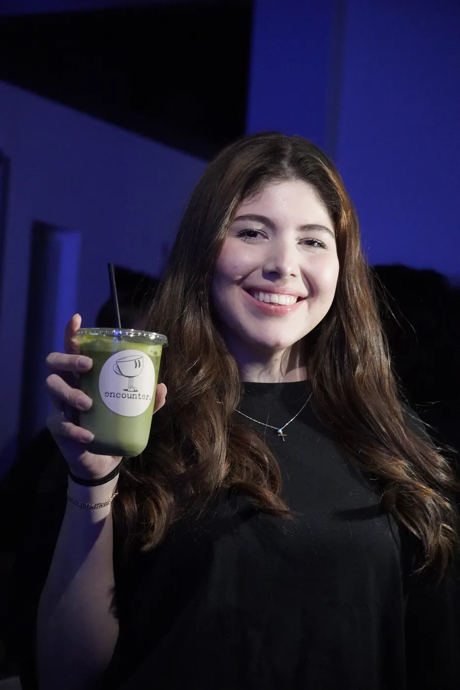 Guest holding an iced matcha latte in an Encounter Coffee branded cup at a DFW event